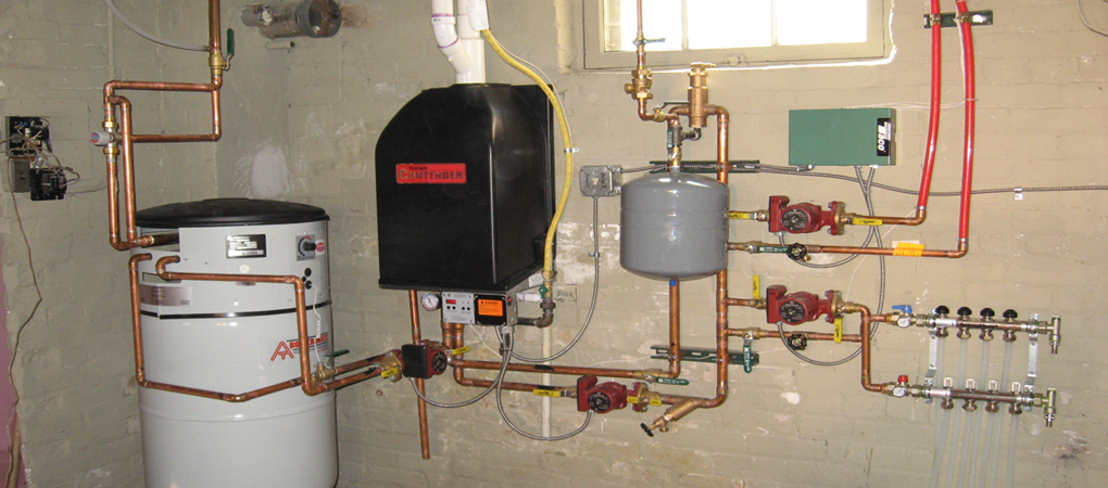 The image showcases a complex gas fitting installation featuring a large water heater, a gas boiler, various copper and brass pipes, valves, and a pressure tank. The setup includes multiple control units and gauges, indicating a comprehensive heating system. The pipes are neatly organised to facilitate gas and water flow, with clear separation of connections leading to different components.